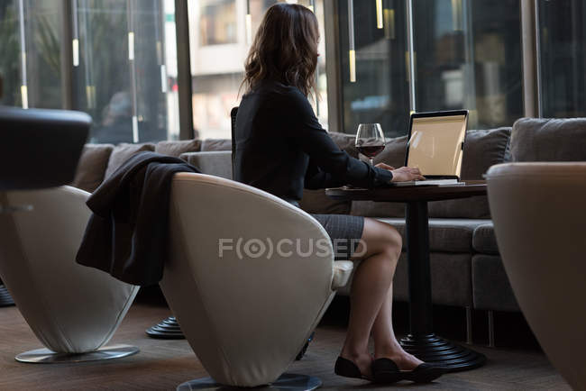 Vista posteriore della donna d'affari che utilizza il computer portatile in hotel — Foto stock