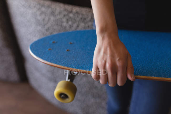 Mid section of female executive standing with skateboard — Stock Photo