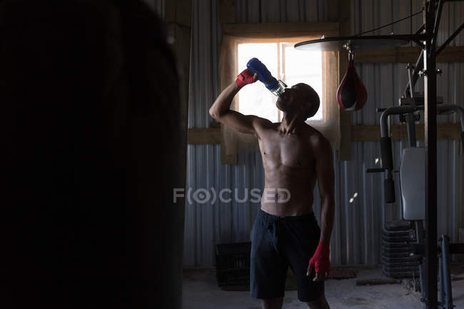 Boxer maschio stanco che beve acqua nel club di boxe — Foto stock