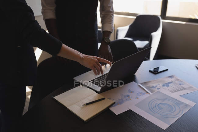Середня секція бізнес-колег обговорює ноутбук в офісі — стокове фото