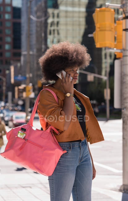 Woman talking on mobile phone in city on a sunny day — Stock Photo