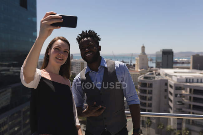 Des collègues d'affaires prennent selfie avec mobile sur la terrasse dans le bureau — Photo de stock