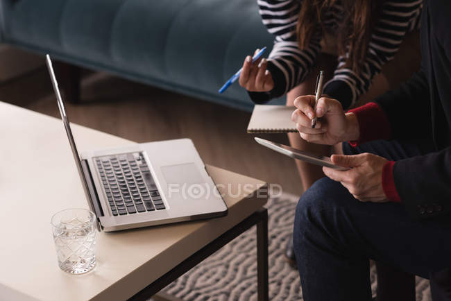 Mid section of executives discussing over digital tablet — Stock Photo
