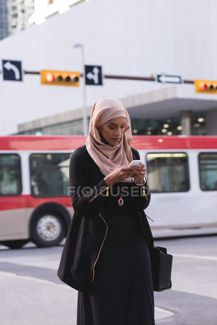 Hijab woman using mobile phone in city street — Stock Photo