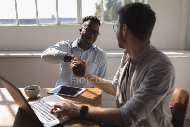 Male executives shaking hands in conference room at office — Stock Photo