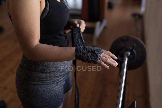 Seção média de boxeador feminino vestindo envoltório de mão em estúdio de fitness — Fotografia de Stock