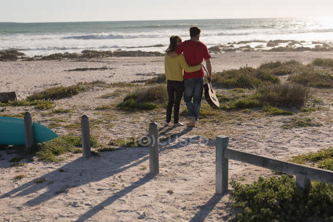 Rear view of couple standing with guitar on beach — Stock Photo