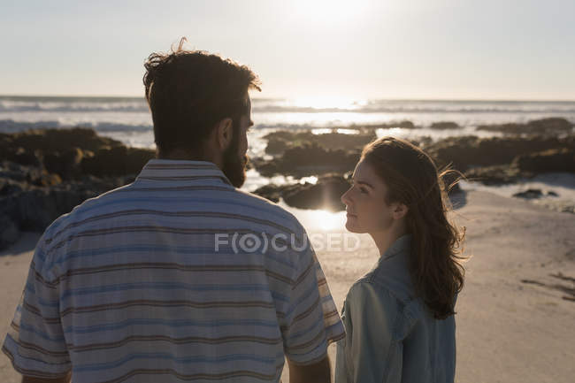 Jeune couple se regardant sur la plage — Photo de stock