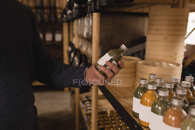 Seção média do homem olhando para a garrafa de grãos no supermercado — Fotografia de Stock