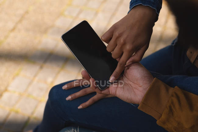 Gros plan d'un couple utilisant un téléphone portable en ville — Photo de stock