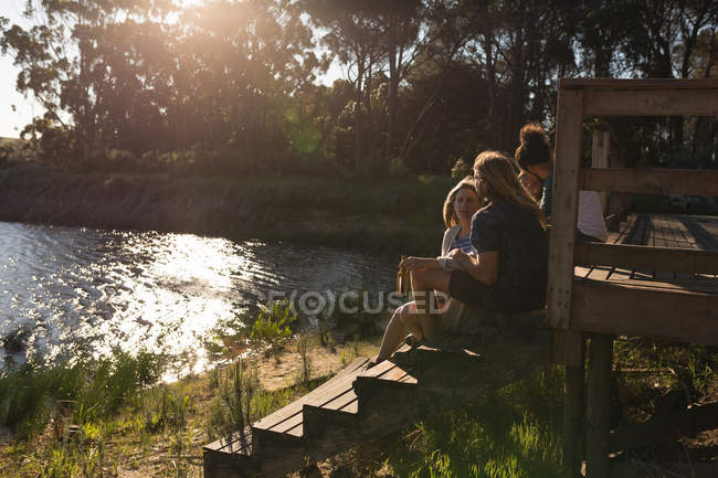 Grupo de amigos hablando entre sí en la cabaña cerca del lago - foto de stock