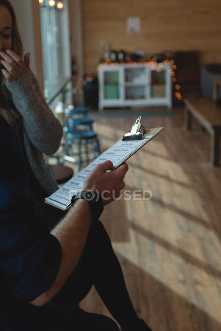 Couple discussing over a clipboard in cafe — Stock Photo