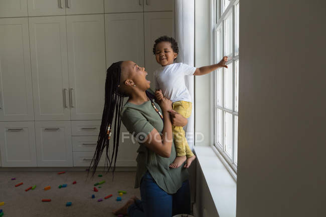Mãe e filho brincando perto da janela em casa — Fotografia de Stock