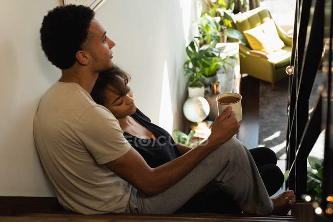 Casal relaxante enquanto toma café nas escadas em casa — Fotografia de Stock