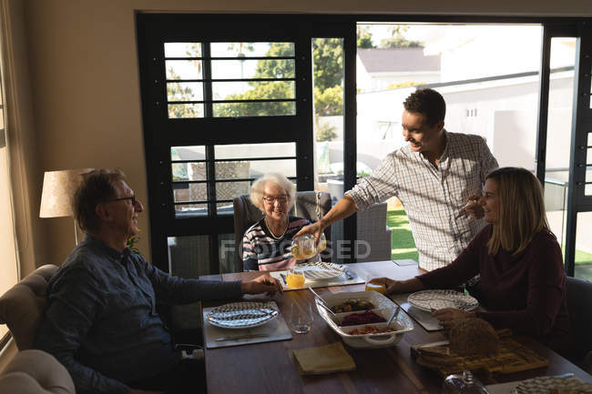 Familia feliz teniendo comida en la mesa de comedor en casa - foto de stock