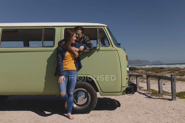 Man embracing woman through car window near beach — Stock Photo