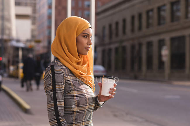 Женщина из хиджаба пьет кофе на городской улице — стоковое фото