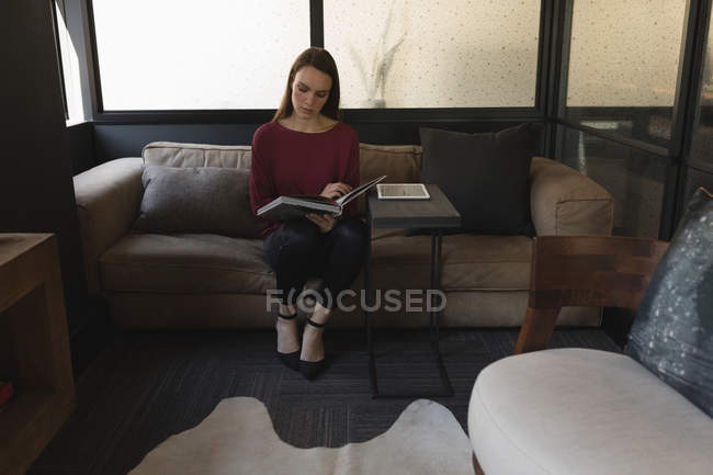 Bela executiva do sexo feminino lendo um livro no escritório — Fotografia de Stock