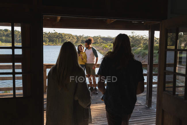 Grupo de amigos se divertindo na cabine perto do lago — Fotografia de Stock