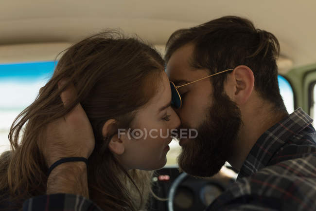 Primer plano de pareja besándose en vehículo en viaje de carretera - foto de stock