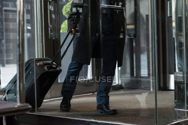 Baixa seção de homem de negócios entrando hotel com bagagem — Fotografia de Stock