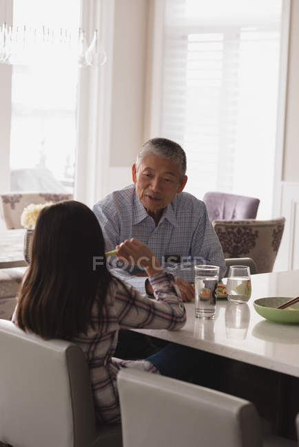 Grandfather and granddaughter interacting with each other on dining table at home — Stock Photo