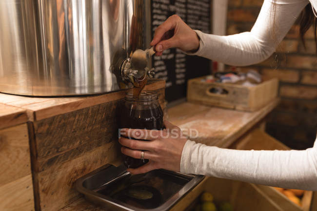 Close-up of woman filling condiment in jar at supermarket — Stock Photo