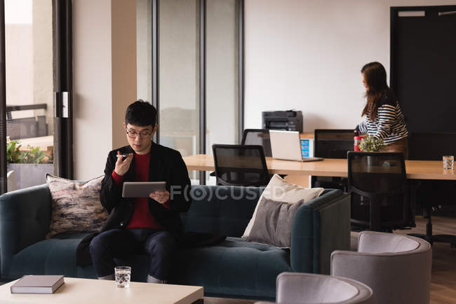Executivo falando no celular enquanto usa tablet digital no escritório — Fotografia de Stock