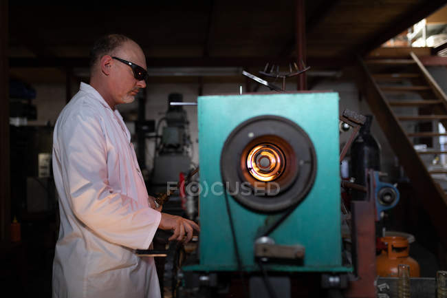 Vista lateral del trabajador masculino que trabaja en fábrica de vidrio - foto de stock