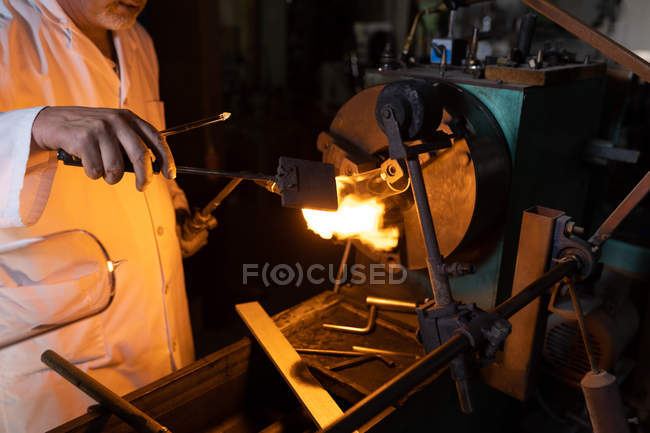Средняя часть работника мужского пола с помощью сварочной горелки на стекольном заводе — стоковое фото