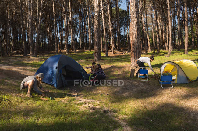 Caminhantes montando uma tenda na floresta em um dia ensolarado — Fotografia de Stock