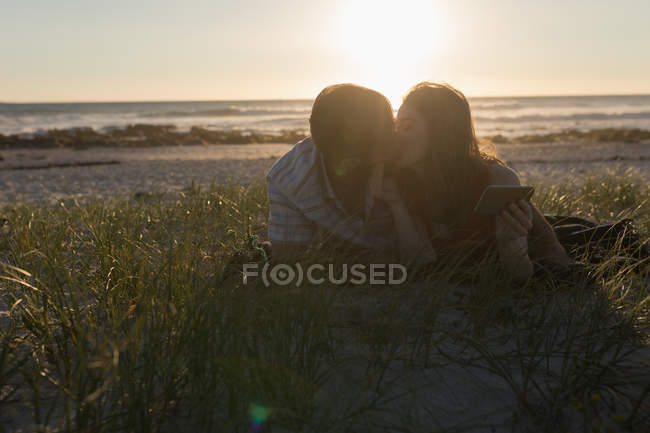 Пара цілується на пляжі під час заходу сонця — стокове фото
