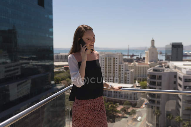 Executivo feminino falando no telefone celular no terraço no escritório — Fotografia de Stock