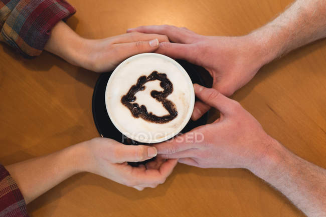 Primer plano de la pareja sosteniendo la taza de café en la cafetería - foto de stock