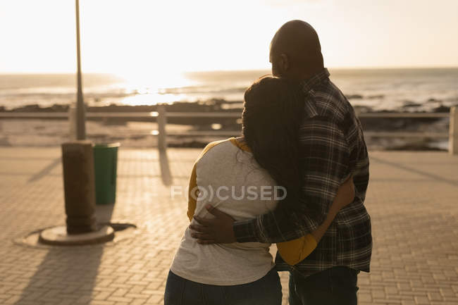 Vista trasera de la pareja abrazándose en el paseo marítimo - foto de stock