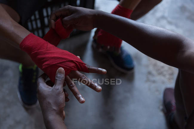 Close-up de treinador ajudando boxeador masculino em amarrar o envoltório da mão na mão — Fotografia de Stock
