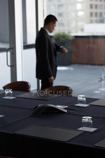 Uomo d'affari che controlla l'ora sul suo orologio nella sala conferenze dell'hotel — Foto stock