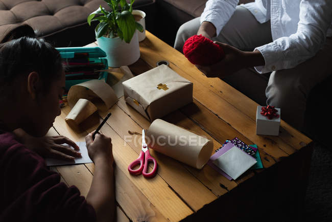 Woman writing name on gift tag in living room at home — Stock Photo