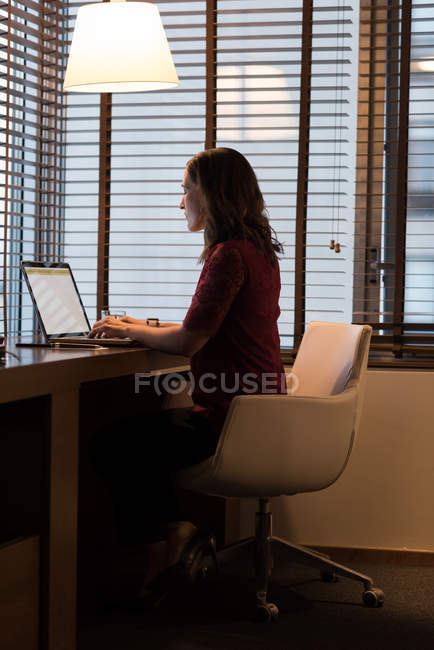 Vista lateral da mulher de negócios usando laptop no quarto de hotel — Fotografia de Stock