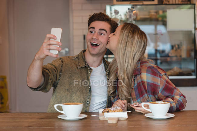 Young couple taking selfie in cafe — Stock Photo
