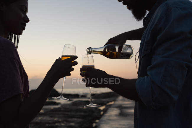 Romantic couple having champagne near sea side — Stock Photo