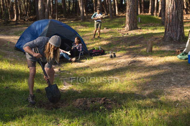 Людина копає грунт в лісі в сонячний день — стокове фото