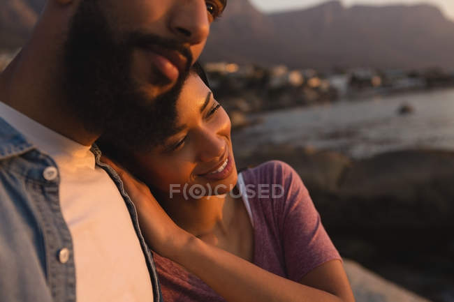 Primer plano de la pareja abrazándose cerca del lado del mar - foto de stock
