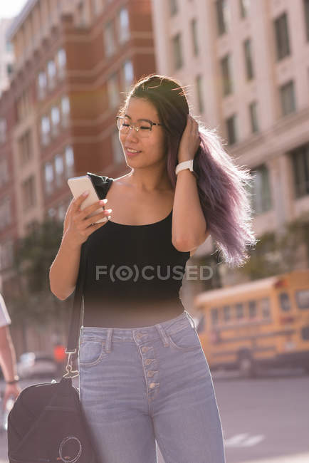 Усміхнена жінка використовує мобільний телефон у місті — стокове фото