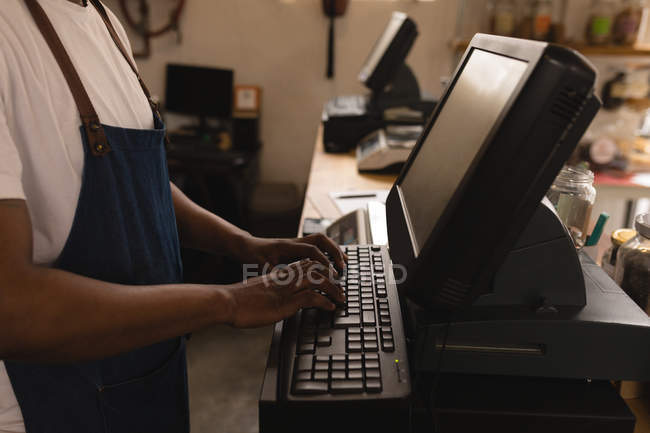 Sección media del personal masculino que trabaja en la computadora en el mostrador - foto de stock