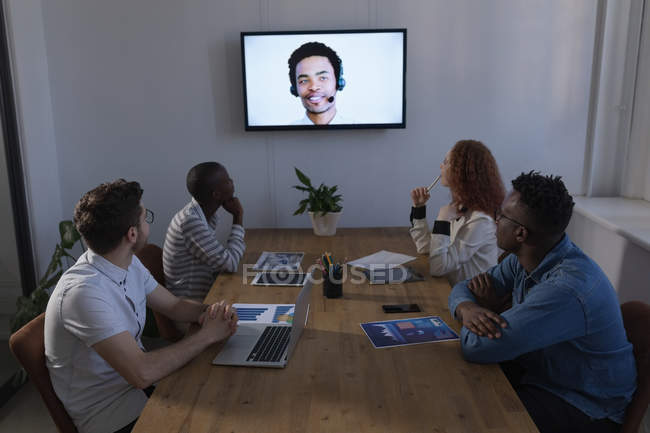 Empresarios interactuando a través de videollamadas en conferencia en la oficina - foto de stock