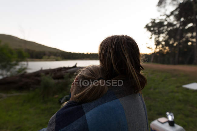 Rear view of couple wrapped in blanket at campsite — Stock Photo