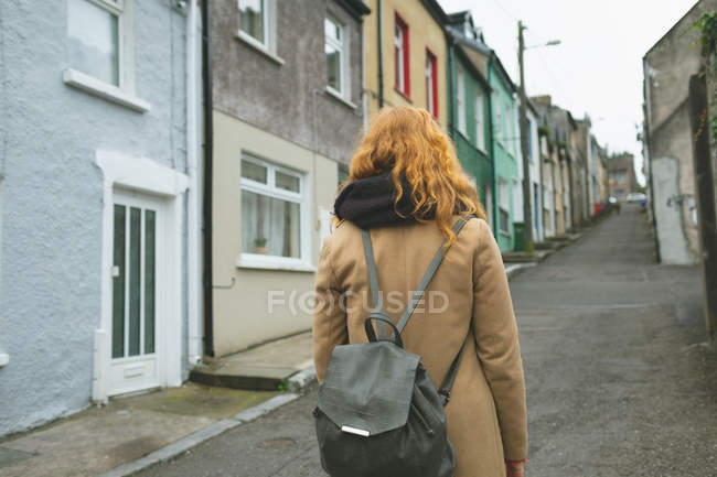 Rear view of redhead woman standing on alley street — Stock Photo