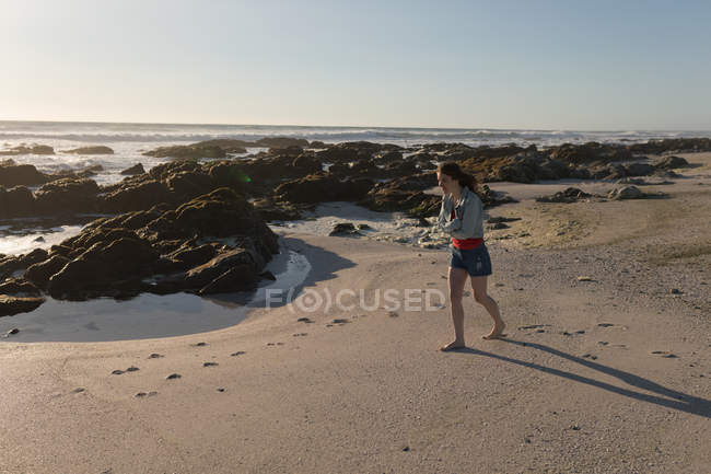Молода жінка, що йде на пляжі — стокове фото