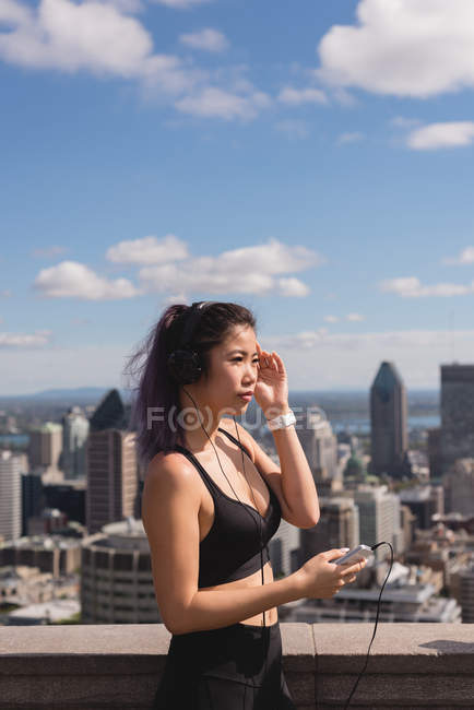 Бегунья слушает музыку на мобильном телефоне в солнечный день — стоковое фото